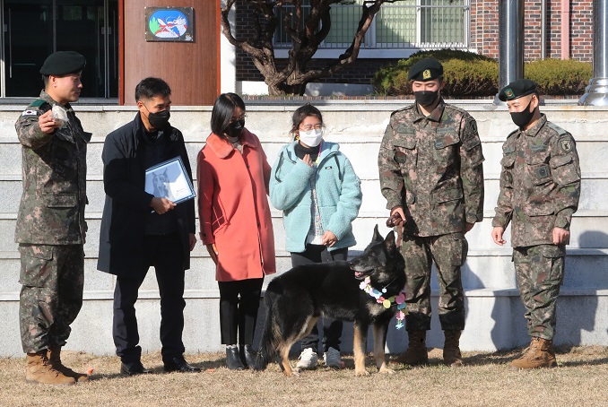 Dalgwan, a scout dog of the Army's 32nd Infantry Division, who played a key role in a 2019 search for missing teenager Cho Eunnuri, poses for a photo with Cho (3rd from R) and her family members at his retirement ceremony at the division's maneuver battalion unit in Sejong, about 120 kilometers south of Seoul, on Dec. 8, 2022. (Yonhap)