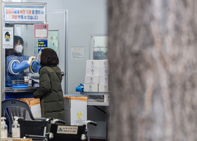 A medical worker conducts a coronavirus test on a woman at a public health facility in Seoul's Songpa Ward on Dec. 30, 2022. South Korea's daily new COVID-19 cases came to 65,207, falling for the third consecutive day amid the government's efforts to contain the virus' wintertime resurgence. (Yonhap)