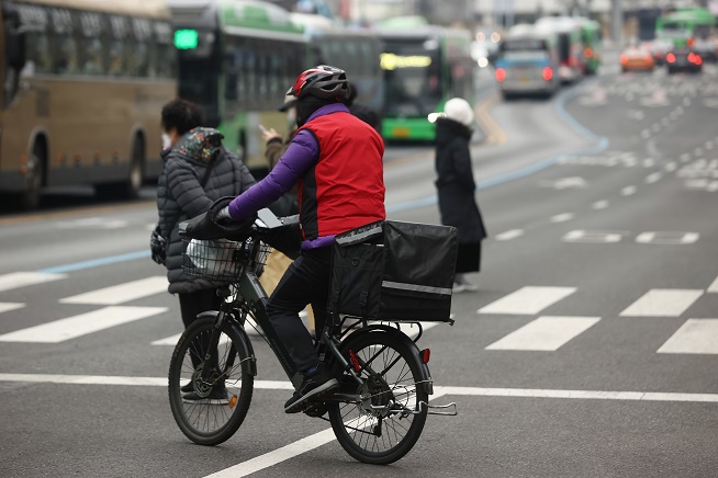 A delivery worker crosses a street in Seoul on Jan. 5, 2023. (Yonhap)
