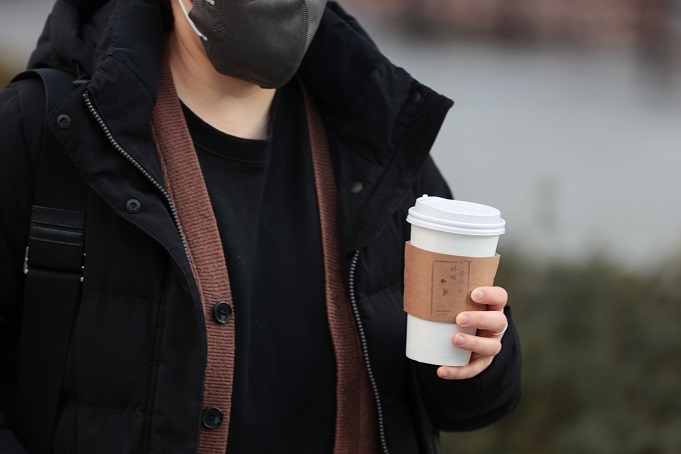 A pedestrian holds a cup of coffee in central Seoul, in this file photo taken Jan. 16, 2023. (Yonhap)