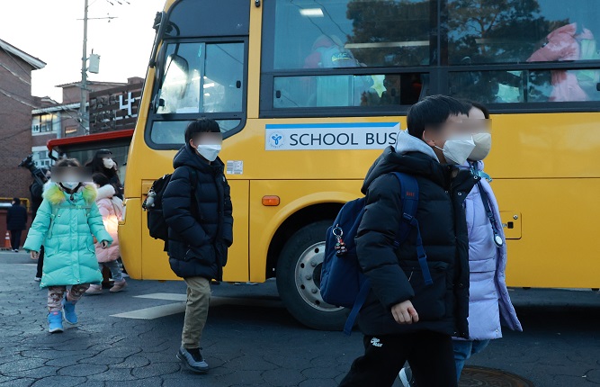 Students wearing face masks get off a school bus in Seoul on Jan. 30, 2023. (Yonhap)