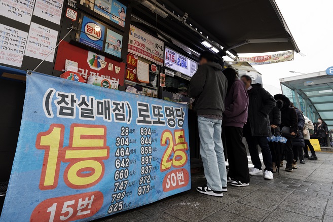 This undated file photo shows people queuing in front of a sales outlet in Seoul to buy Lotto tickets. (Yonhap)