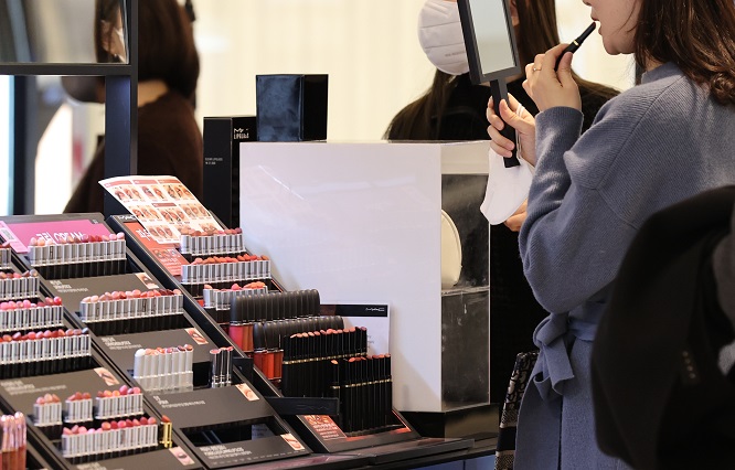 A shopper tries on makeup at a department store in central Seoul on Jan. 29, 2023. (Yonhap)