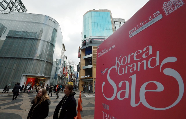 People walk past a sign promoting the Korea Sales Festa, one of the largest shopping events in South Korea, in the tourist district of Myeongdong, central Seoul, on Jan. 31, 2023. (Yonhap)