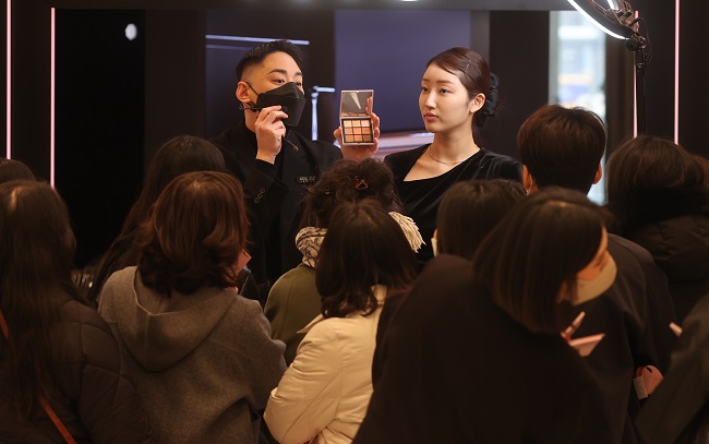 People watch a makeup demonstration at a department store in Seoul on Feb. 1, 2023, after the government lifted an indoor mask mandate earlier in the week. (Yonhap)