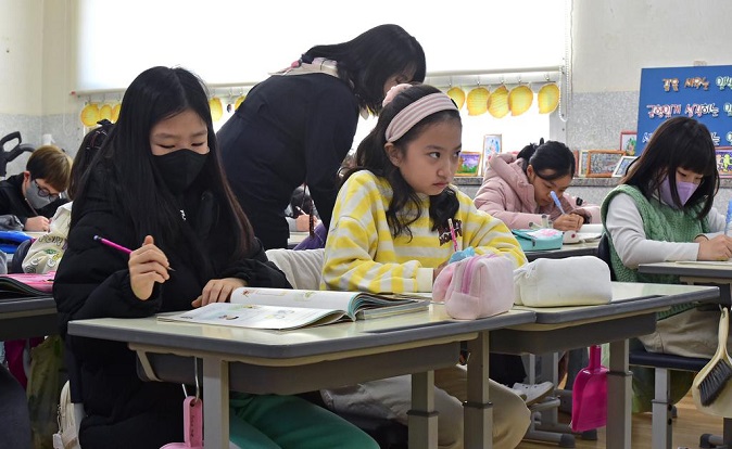 Students shedding their masks and others wearing them attend a class at an elementary school in the southeastern city of Daegu on Jan. 30, 2023. (Yonhap)