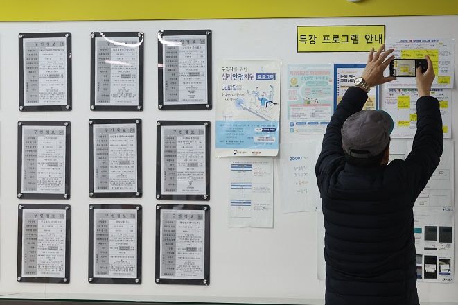 An elderly man takes a photo of job information on the bulletin board at an employment center in Mapo, western Seoul, on March 15, 2023. (Yonhap)