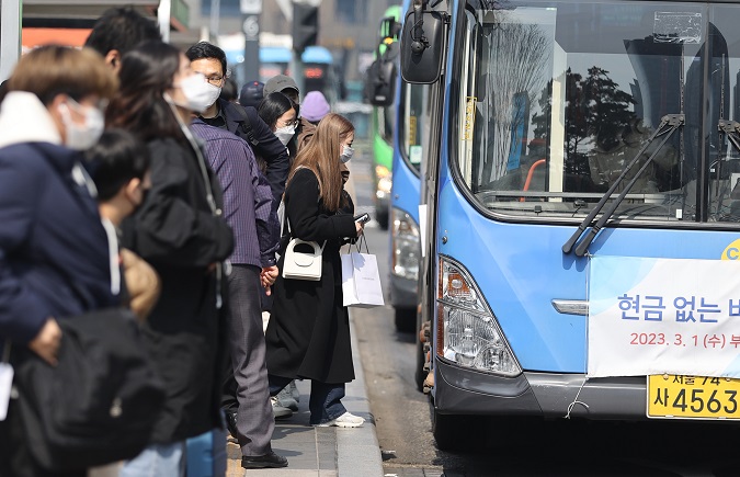 People wait for a bus at a bus stop near Seoul Station in Seoul on March 19, 2023. (Yonhap)