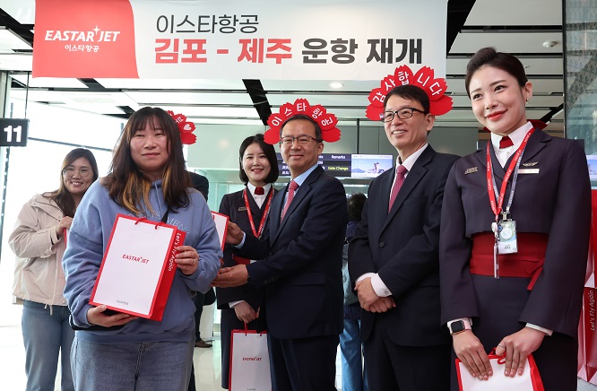 Eastar Jet CEO Cho Joong-seok (4th from L) and company officials pose for a photo with a passenger (2nd L) who won a promotional event celebrating the budget carrier's flight resumption after three years at the domestic terminal of Gimpo International Airport on March 26, 2023. (Pool photo) (Yonhap)