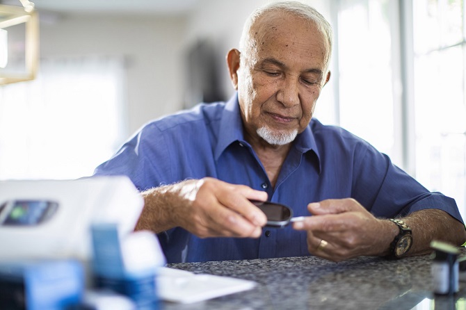 A man takes a blood glucose reading at home