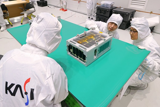This undated photo provided by the Korea Aerospace Research Institute (KARI) shows officials inspecting a microsatellite developed by the Korea Astronomy and Space Science Institute, codenamed SNIPE, at the Naro Space Center in Goheung, South Jeolla Province.