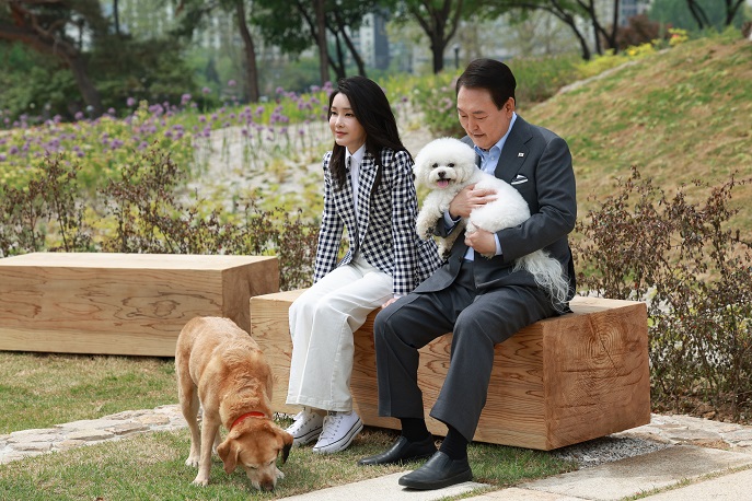 President Yoon Suk Yeol (R) and first lady Kim Keon Hee pose for a photo with Sunny and a retired guide dog, named Saeromi (ground), at Yongsan Children's Garden in front of the presidential office in Seoul on May 4, 2023, in this photo provided by the presidential office.
