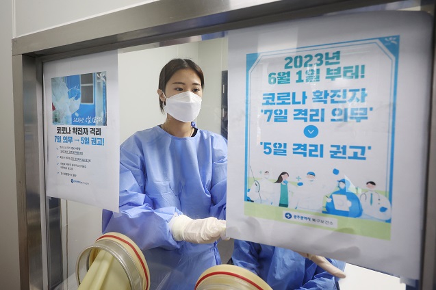 A medical worker puts up a notice that notifies the mandatory isolation period will be reduced to five days as a recommendation, from the seven-day requirement, starting June 1 at a COVID-19 treatment facility in Gwangju, 267 kilometers south of Seoul, on May 31, 2023. (Yonhap)