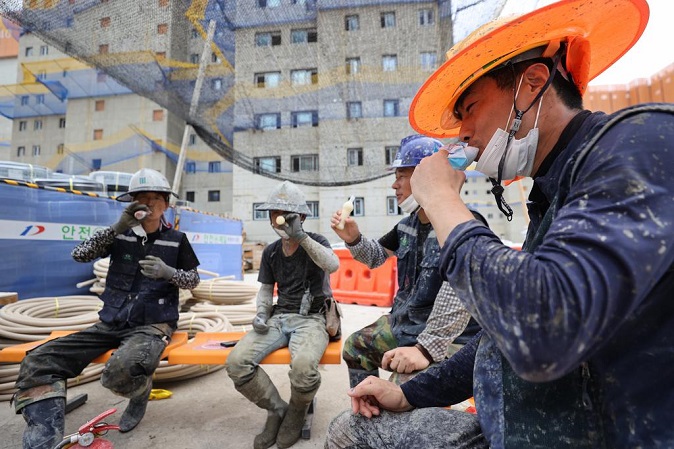 Construction workers eat ice cream to cool off from the sweltering heat during a break at an apartment construction site in Incheon, 40 kilometers west of Seoul, on July 20, 2021. (Yonhap)