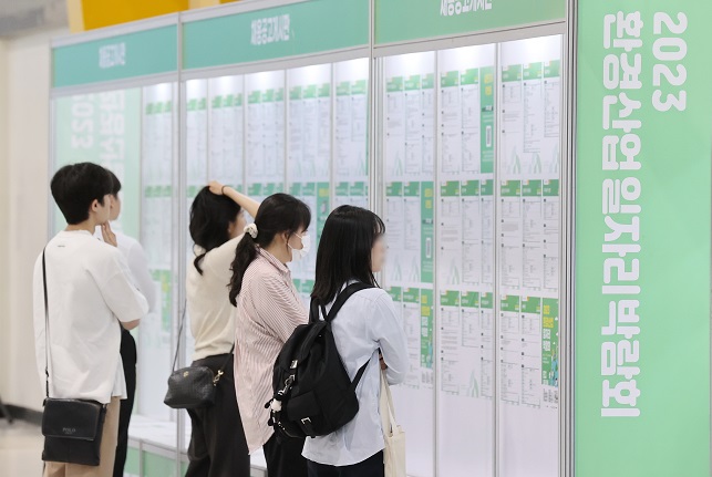 This file photo taken May 16, 2023, shows job seekers looking at job information posted on a bulletin board during a job fair in Seoul. (Yonhap)