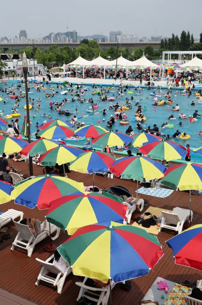 As the scorching heat wave reaches its peak, people seek relief by enjoying a refreshing swim in the swimming pool at Han River Park in Yeouido, Seoul, on the afternoon of Sunday.