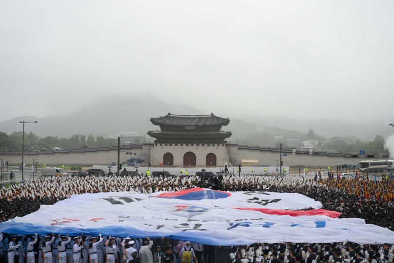 Soldiers unfurl a large Korean flag in front of Gwanghwamun Gate after a march through the city.