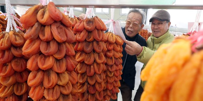 Auctioneers inspect dried peeled persimmons, known as "gotgam," in Hamyang, a town in South Korea's southeast province of South Gyeongsang, on Dec. 7, 2023, as they take part in this year's first auction for the Korean delicacy.