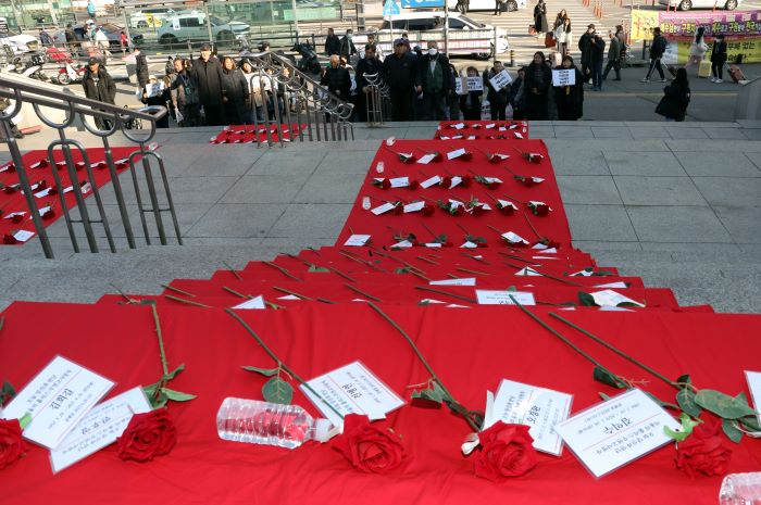 Behind the press conference, roses and name tags lay in memory of Homeless, who died in squalor. 