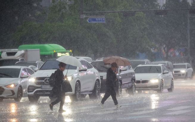On May 16, amid rainfall, pedestrians walk with umbrellas at Gwanghwamun Intersection in Seoul. (Yonhap)