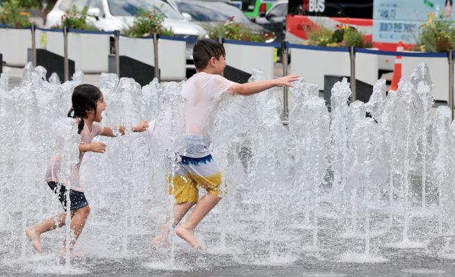 As sweltering heat continued across South Korea on July 1, with heat wave advisories in effect for most regions, young children enjoy cooling off at the ground fountain in Gwanghwamun Square, Seoul. (Yonhap)