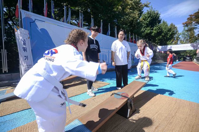 Children participating in the Foreigners’ Taekwondo Festival experience neolttwigi, a traditional Korean seesaw game. (Image courtesy of Kukkiwon)