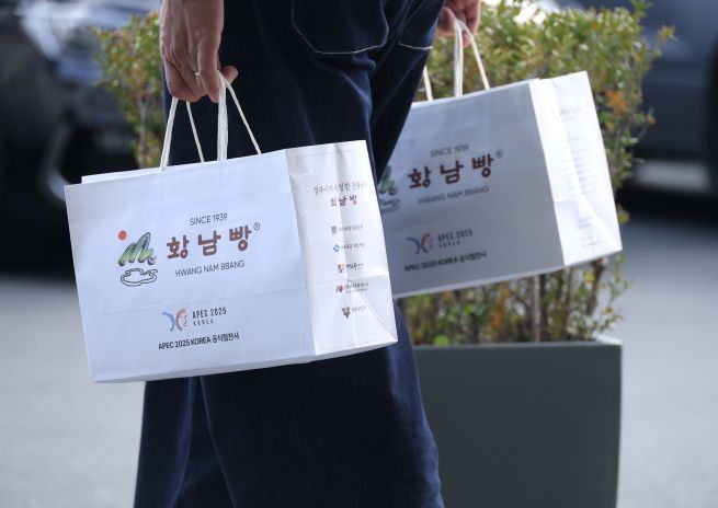 On November 1, citizens carry boxes of Hwangnam Bread purchased from the bakery’s main branch in Gyeongju, an official sponsor of the 2025 Asia-Pacific Economic Cooperation (APEC) Summit. The bread drew attention after Chinese President Xi Jinping, who received it as a gift from President Lee Jae Myung during the summit, reportedly expressed his appreciation, saying he “enjoyed it very much.” (Yonhap)