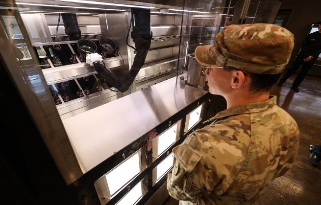 A U.S. soldier waits for a robot-cooked meal on November 28 at “Market 19,” an automated dining facility installed at Camp Walker of the U.S. Army’s 19th Expeditionary Sustainment Command in Nam-gu, Daegu. The facility, the first automated dining hall in the U.S. Army, will operate on a trial basis for six months starting this month.