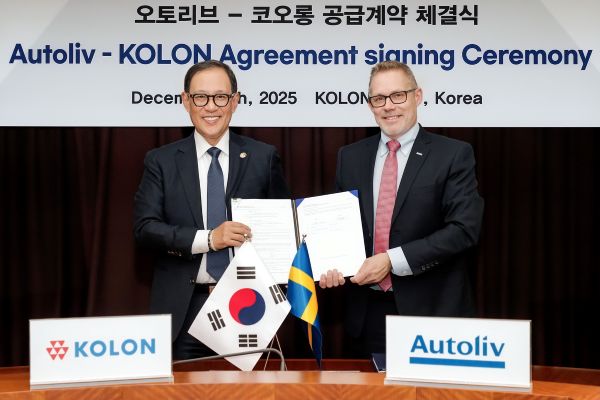 This photo, taken on Dec. 8, 2025, and provided by Kolon Industries, shows the company's CEO Huh Sung (L) and Christian Swahn, executive vice president overseeing global supply chain management at Autoliv, posing after signing an airbag materials supply deal at Kolon Industries' headquarters in Gwacheon, just south of Seoul. (Yonhap)