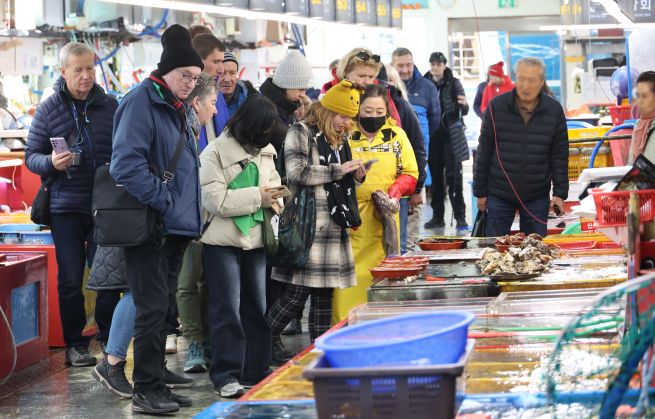 Foreigners look around a fish market in the southeastern city of Busan on Dec. 4, 2025. (Yonhap)