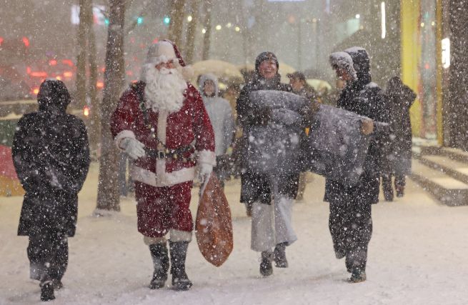 A foreign tourist dressed as Santa Claus enjoys the first snowfall near Hongdae in Mapo District, Seoul, on December 4. (Yonhap)