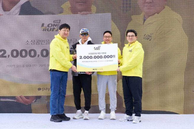 At the offline “2025 Long Run” event held on Dec. 5 at Hanam Misa Lakeside Park in Hanam, Gyeonggi Province, singer Sean (second from left), Kakao Pay Vice President Cha Seung-jin (second from right) and Vice President Lee Yun-geun (far left) present a 2 billion won donation for small business owners to Lee Won-tae, secretary-general of the Together Working Foundation (far right). (Photo provided by Kakao Pay)