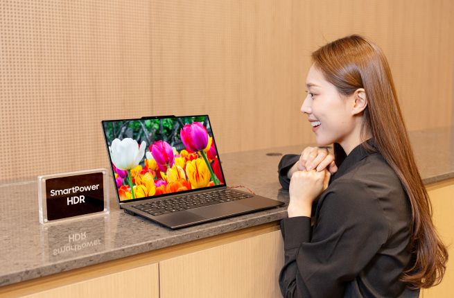 This photo released by Samsung Display Co. on Jan. 7, 2026, shows a model posing for a photo with a laptop equipped with the SmartPower HDR technology, jointly developed with U.S.-based Intel Corp. (Yonhap)