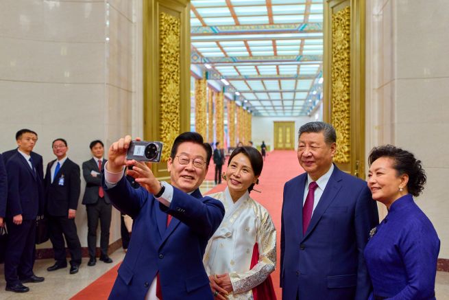 South Korean President Lee Jae Myung (L) and his wife, Kim Hea Kyung (2nd from L), take a selfie with Chinese President Xi Jinping (2nd from R) and his wife, Peng Liyuan, by using a Xiaomi smartphone following a state dinner for the South Korean leader in Beijing on Jan. 5, 2026. The smartphone was gifted to Lee by Xi during their first summit talks in Gyeongju, South Korea, in November 2025. (Pool photo) (Yonhap)