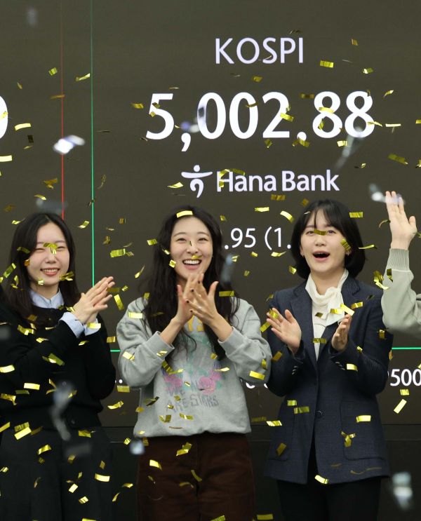 Currency traders rejoice in the dealing room of Hana Bank in Seoul on Jan. 22, 2026, as a financial data screen shows the benchmark Korea Composite Stock Price Index having topped the 5,000-point level in early trading. South Korean stocks opened sharply higher and hit another intraday record. (Yonhap)