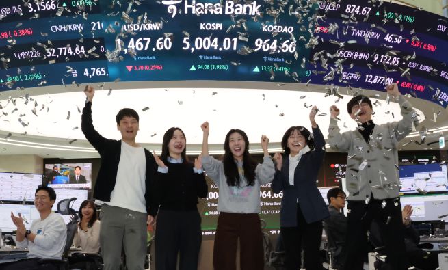 Currency traders rejoice in the dealing room of Hana Bank in Seoul on Jan. 22, 2026, as a financial data screen shows the benchmark Korea Composite Stock Price Index having topped the 5,000-point level in early trading. South Korean stocks opened sharply higher and hit another intraday record. (Yonhap)